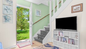 Ein Wohnzimmer mit Treppe, Fernseher und Bücherregal.
