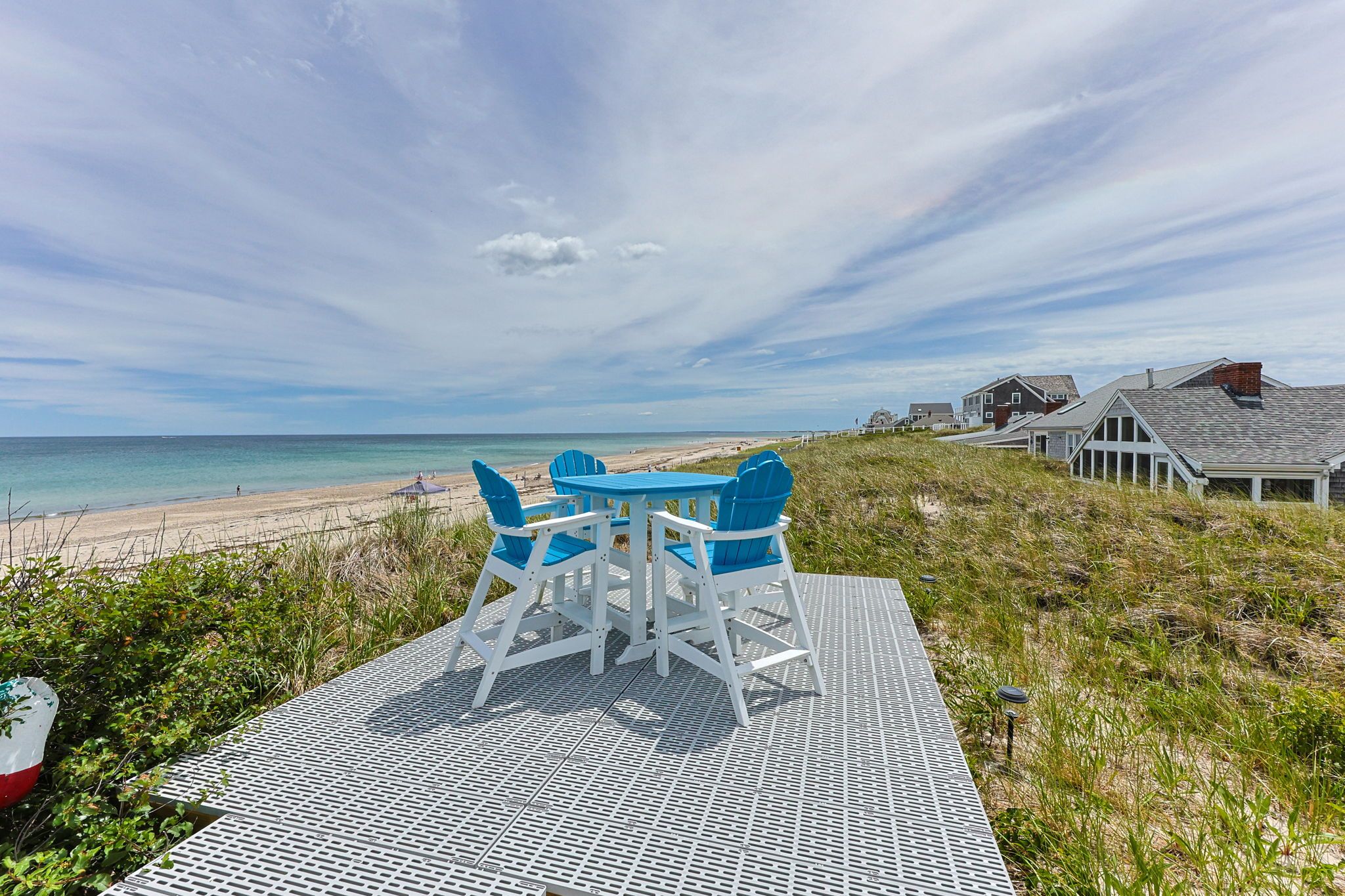 A beachside table with chairs, overlooking a sandy beach and ocean.