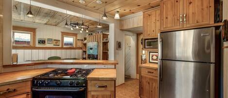 Une cuisine avec des meubles en bois, un réfrigérateur en acier inoxydable, une cuisinière et un four à micro-ondes.