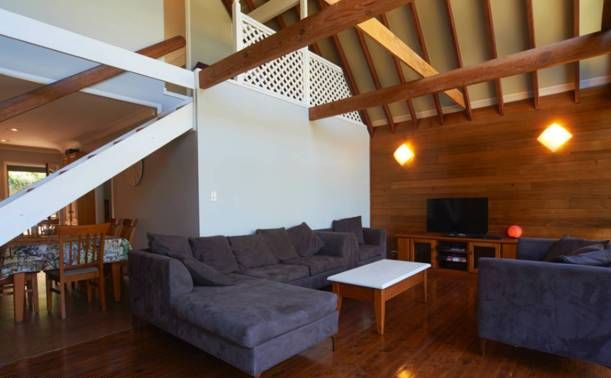 A spacious living area with a wooden ceiling, a sofa, a coffee table, and a TV.