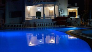 Vista nocturna de una piscina con el reflejo de su borde.