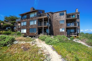 A multi-story building with balconies, a wooden facade, and a clear sky.