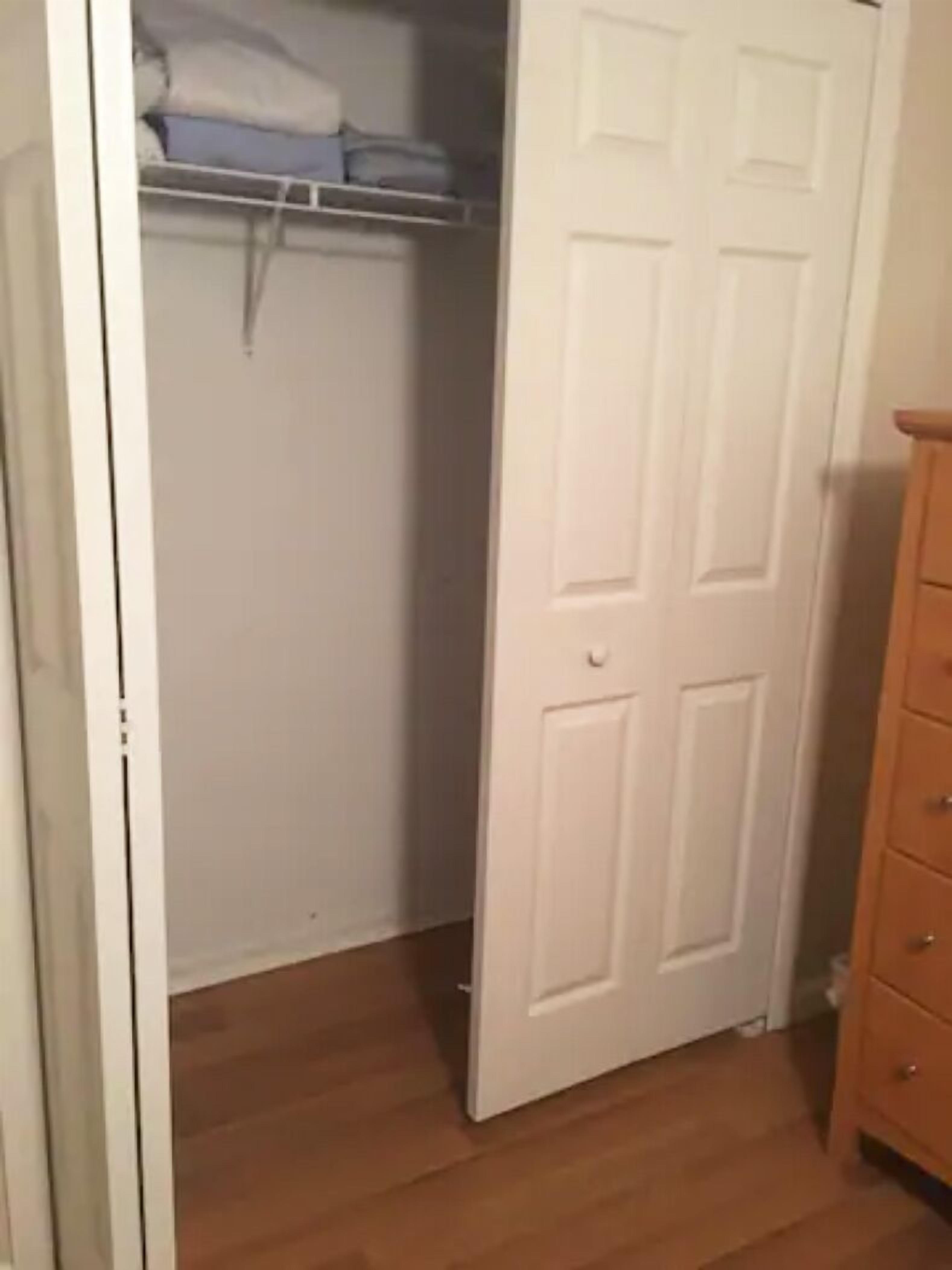 Ein Zimmer mit Holzboden, einer weißen Tür und einem Holzschrank.