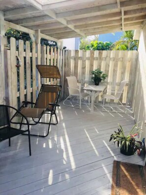 Un patio couvert avec une terrasse en bois, une table et des chaises, et une plante en pot.