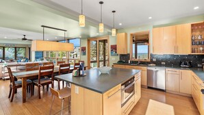 Une cuisine moderne avec des meubles en bois, un îlot central et des luminaires suspendus.