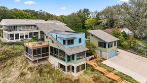 Une maison moderne à plusieurs étages, dotée d’une grande terrasse, d’un garage et d’un jardin bien entretenu.