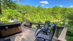 Una terraza con un jacuzzi, dos sillones reclinables y un banco de madera.