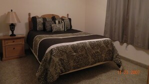 A bedroom with a bed, nightstand, lamp, and curtains. - Gateway to Zion - Sleeps 8! (Hurricane)