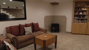 A living room with a brown sofa, a coffee table, a fireplace, and a bookshelf. - Gateway to Zion - Sleeps 8! (Hurricane)