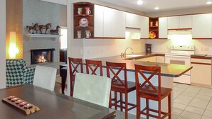 A modern kitchen with white cabinets, a central island, and a dining area with wooden chairs.