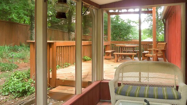 A covered patio with wicker furniture, a table, and a view of the backyard.