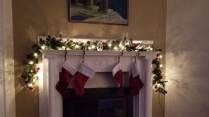 A fireplace with a garland and stockings, a painting above it, and a patterned rug in front. - Spacious Condo In Cranston/Providence Line - 2 Bed (Cranston)