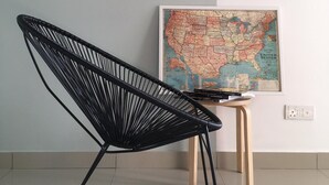 Una silla de estructura metálica negra en una habitación con suelo de baldosas y un mapa sobre una pequeña mesa de madera.