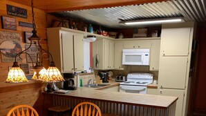 A kitchen with wooden cabinets, a white stove, and a dining area with a wooden table and chairs.