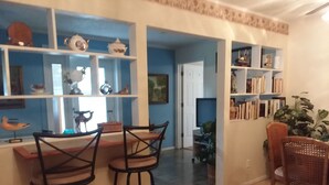 A dining area with a table and two bar stools, a bookshelf with various items, and a television in the background. -  Country  Cottage Home (Bradenton)