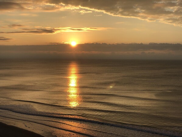 Un coucher de soleil sur une mer calme aux vagues douces.