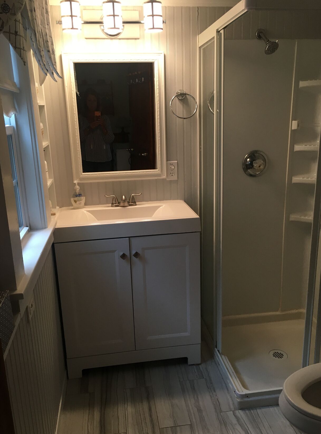 A bathroom with a white vanity, a mirror, a shower, and a toilet.
