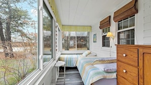 Une chambre avec une fenêtre, un lit, une commode et une lampe.