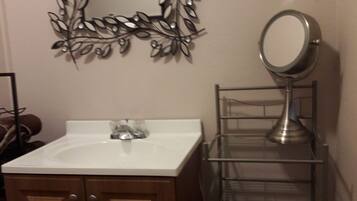 Une salle de bain avec un lavabo blanc, un miroir et un élément décoratif en métal fixé au mur.