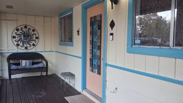 Un porche avec un banc, un élément décoratif mural et une porte dotée d’une fenêtre.