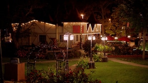 A well-lit outdoor area with a garden, a horse statue, and a building with a sign reading "Notre Gift".