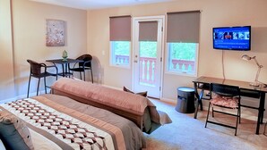 A bedroom with a bed, a desk, a chair, a television, and a balcony.