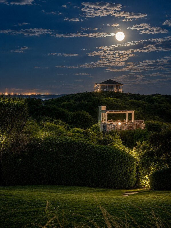 A house on a hill with a moon in the sky.