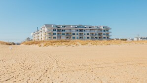 A multi-story hotel with balconies, located on a sandy beach with clear skies. - Sandbridge Beach,Virginia Beach Penthouse Condominum (Virginia Beach)