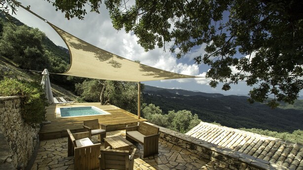 A wooden deck with a pool, stone flooring, and outdoor furniture. - Charming and traditional small stone house. (Corfu)