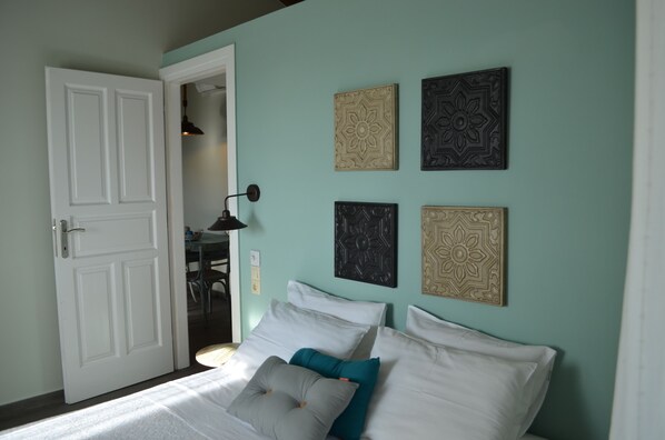 Un dormitorio con una cama, una puerta y cuatro paneles decorativos en la pared.