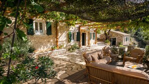 A stone patio with wicker furniture and a pergola. - Charming and traditional small stone house. (Corfu)