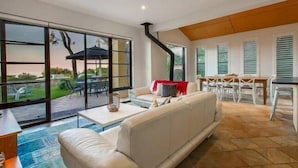 A modern living room with a sofa, a coffee table, and a dining area with a table and chairs. - Panoramic Bay Views - Pet friendly & only a  5 minute stroll to town (Dunsborough)