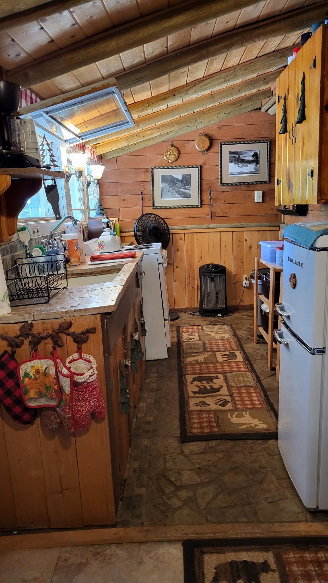 A cozy kitchen with wooden cabinets, a refrigerator, and a dining area with a table and chairs.