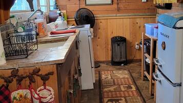 A cozy kitchen with wooden cabinets, a refrigerator, and a dining area with a table and chairs.