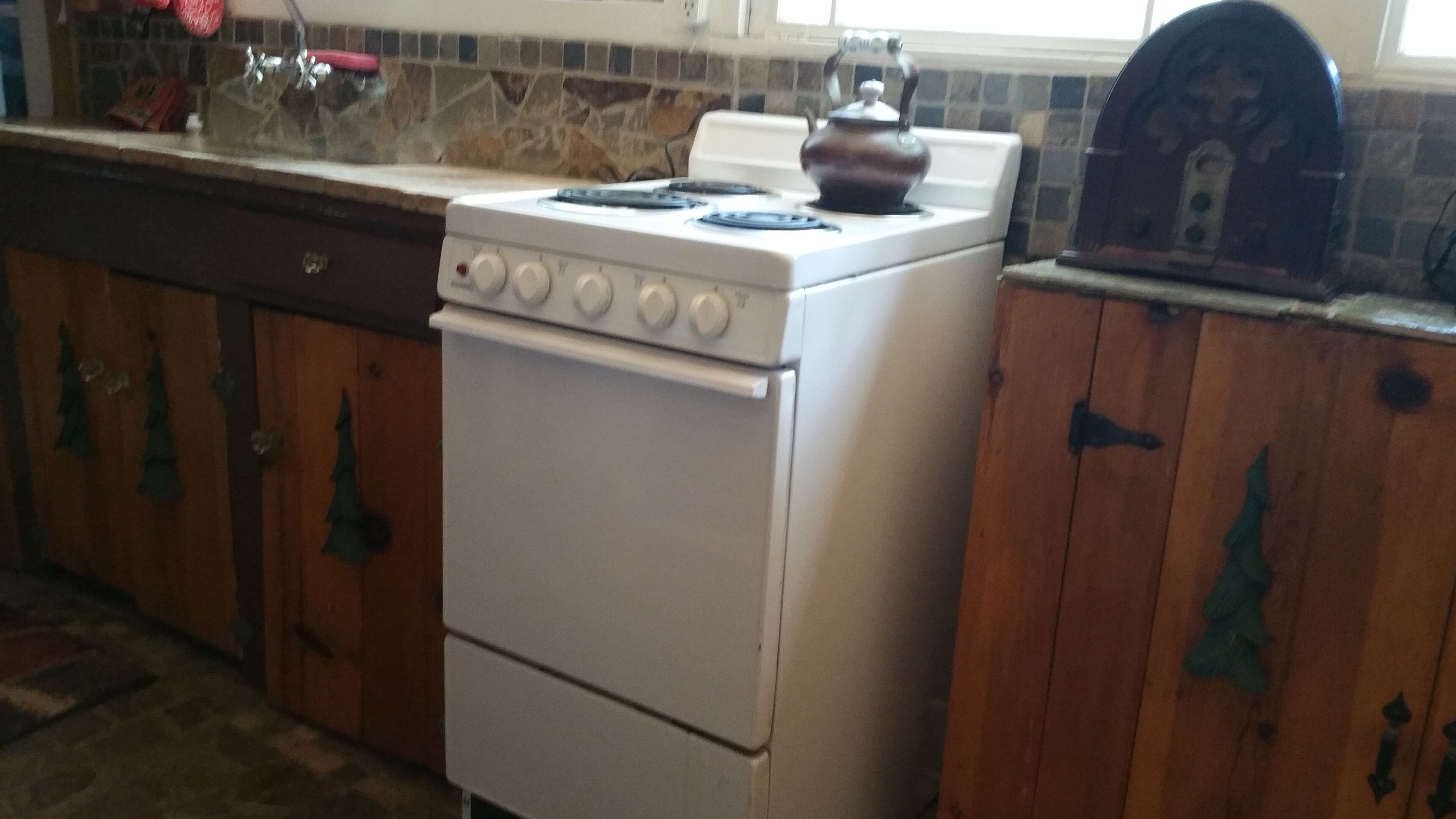 A kitchen with a white stove, wooden cabinets, and a tiled backsplash.