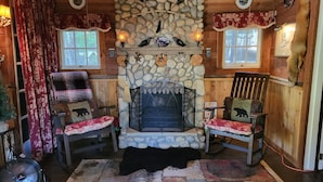 A cozy cabin interior with a stone fireplace, two wooden chairs with bear-themed cushions, and a Christmas tree. -  11 miles to Kings Canyon Natl Park with Wi-Fi (Miramonte)