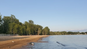 A beach with picnic tables and a sandy shore. - Slow down…You’re on Island Time (Isle La Motte)