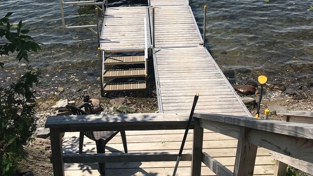 A wooden pier extending into calm water, with a bench at the end. - Slow down…You’re on Island Time (Isle La Motte)