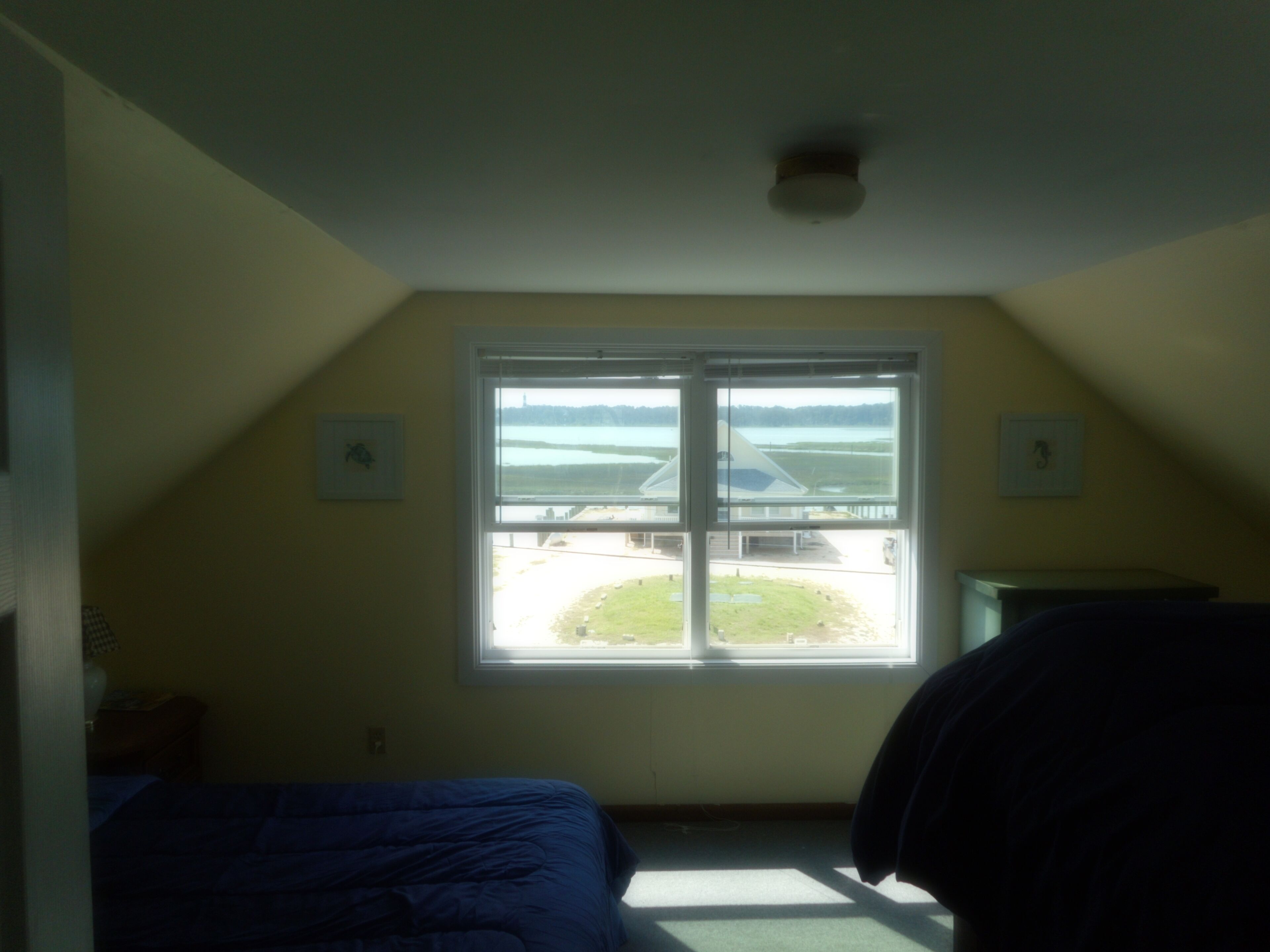 A room with a large window, a bed, a desk, and a chair.