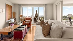 Un salon spacieux avec une grande fenêtre, un canapé, une table basse et un fauteuil.