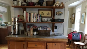 Eine Holz-Küche mit einer zentralen Kochinsel, Regalen darüber mit verschiedenen Küchengeräten und Büchern, sowie einem Essbereich mit Holzmöbeln.