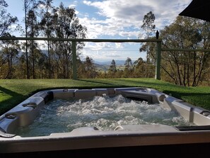 Een hottub met uitzicht op een gazon en bomen.