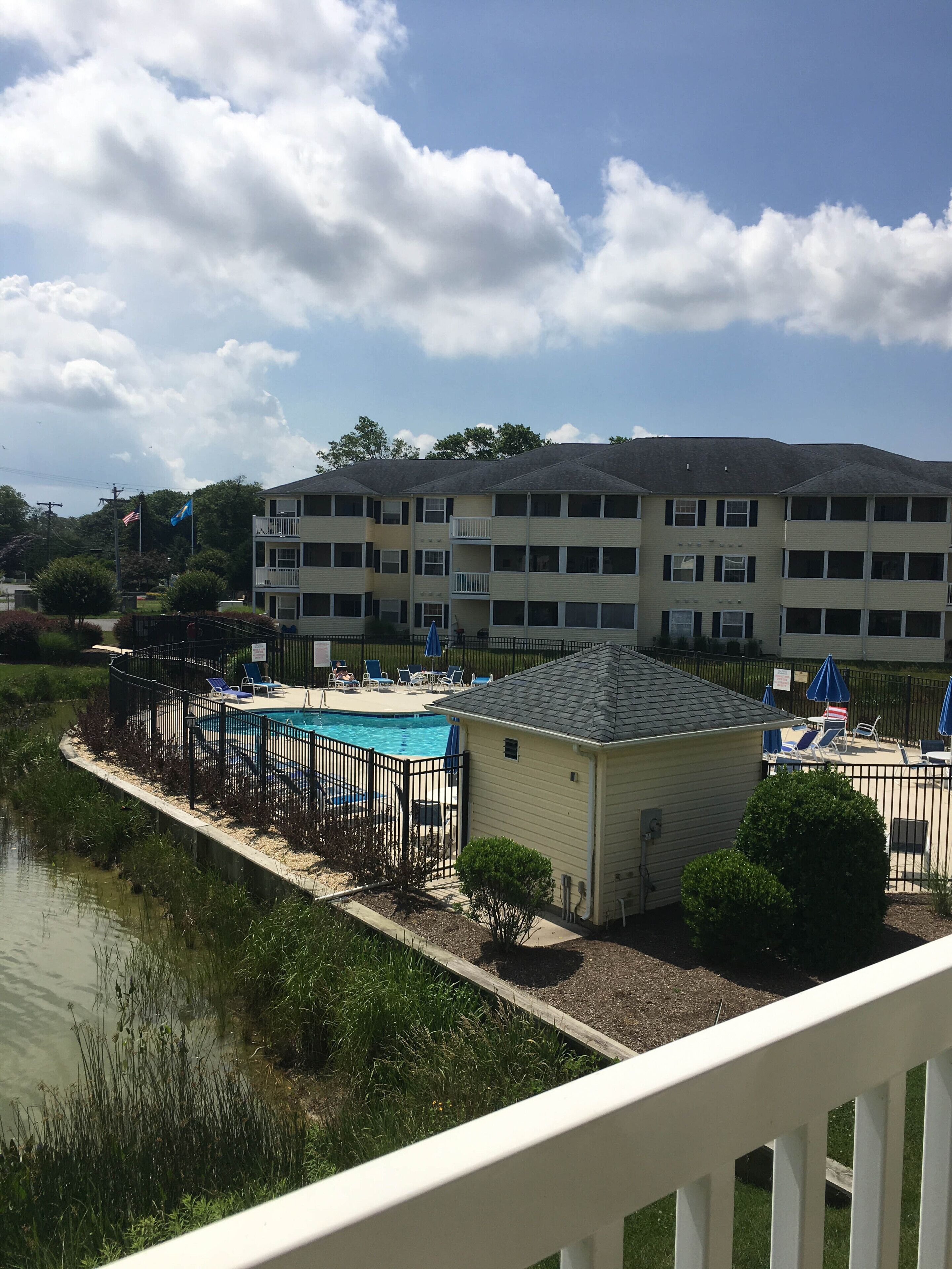Un edificio residencial con piscina, un área de terraza cercada y vista a un cuerpo de agua.