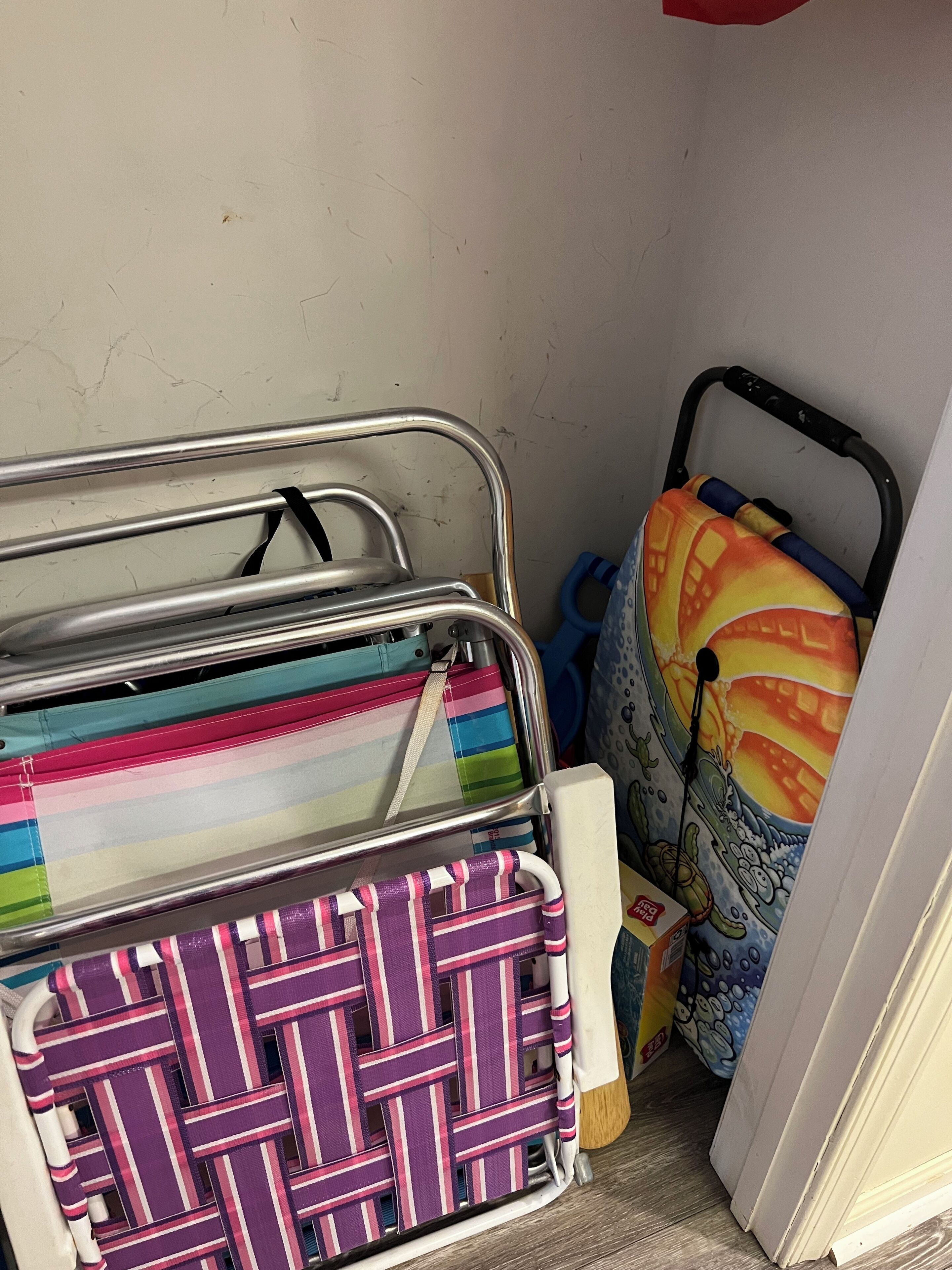 Un área de almacenamiento con estanterías metálicas que contienen bolsas coloridas a rayas y un colchón con un diseño de caricatura.
