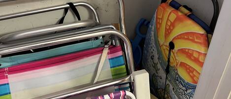 Un área de almacenamiento con estanterías metálicas que contienen bolsas coloridas a rayas y un colchón con un diseño de caricatura.