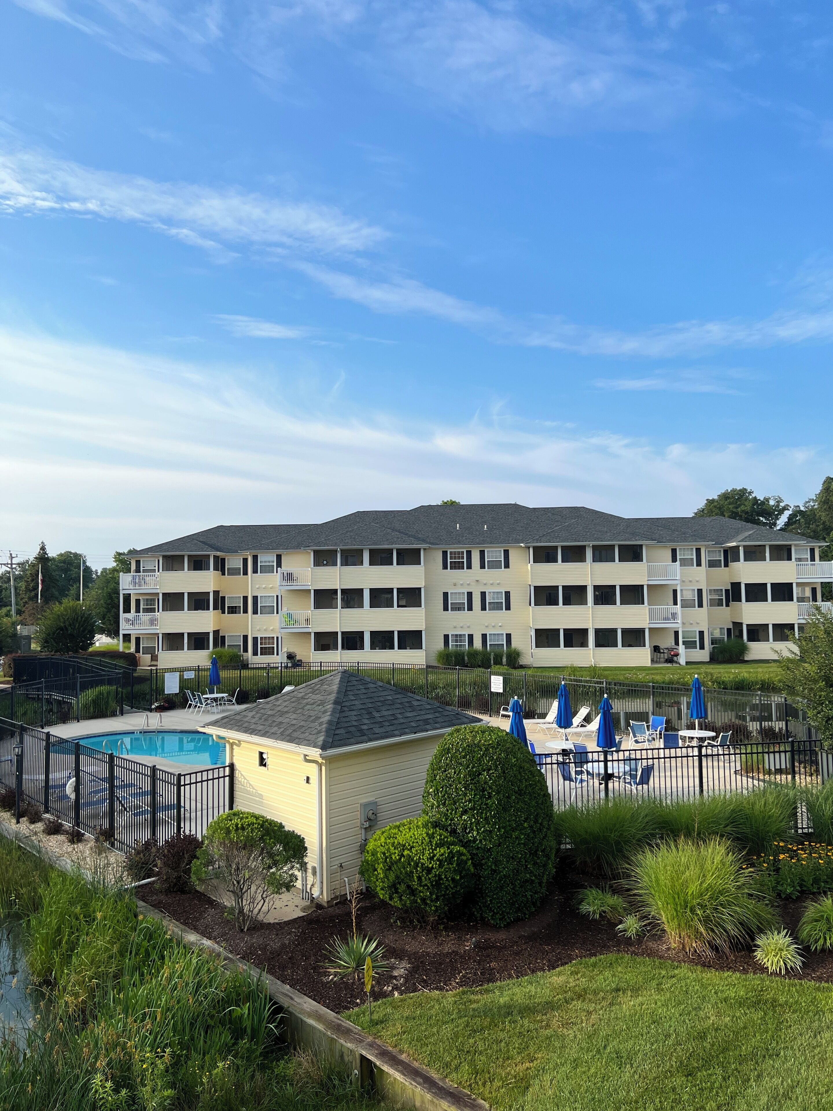 A multi-story apartment building with a swimming pool and outdoor seating area.
