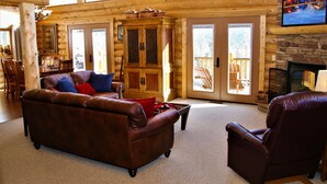 A log cabin interior with a leather sofa, a wooden cabinet, and a fireplace.