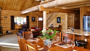 A wooden cabin interior with a dining area, living room, and kitchen.