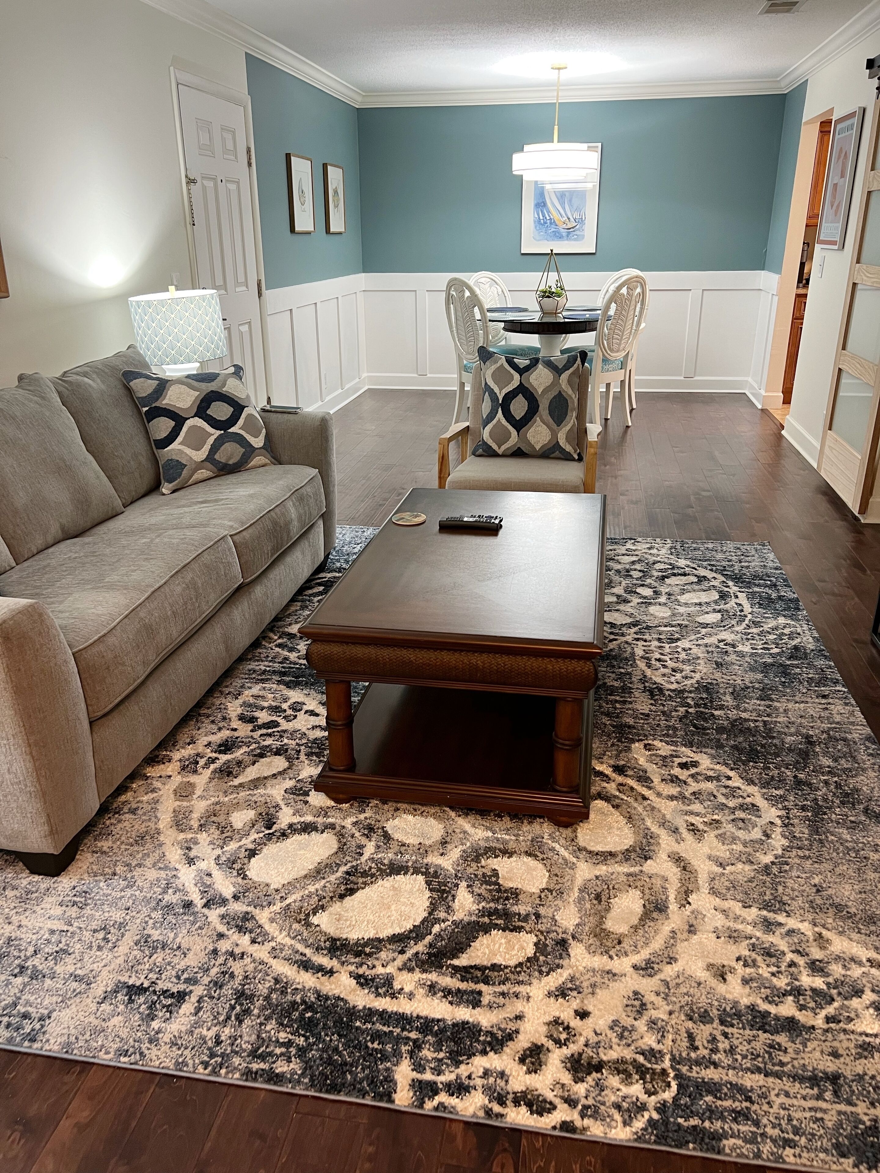 A living room with a sofa, coffee table, and patterned rug.