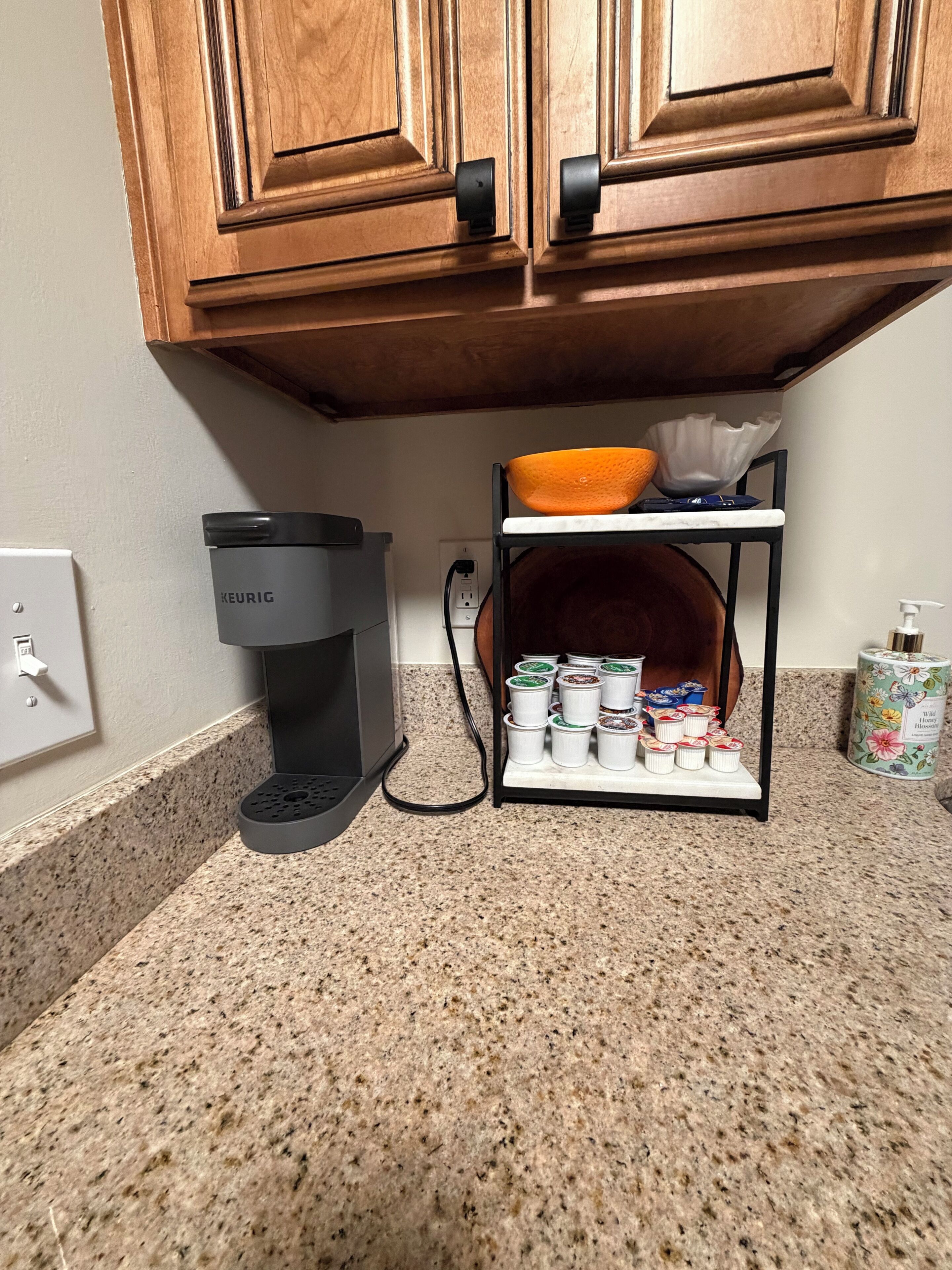 A kitchen with a Keurig coffee maker, a bowl, a shelf with containers, and a floral canister.
